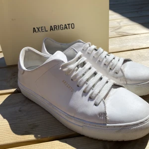 Axel Arigato skor  strl 38 - Säljer mina Arigato skror då jag ska köpa ett par andra skor. Nypris 2249kr! Säljer väldigt billigt då de är väl använda som man kan se på sista bilden. Finns defekter (sulan mm) Skriv om ni vill ha fler bilder🥰 (de första bilderna är från förra sommaren)