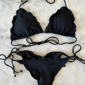 Svart bikini med scrunch - Svart triangelbikini, trosor i brazilian-modell med scrunch. Från Nelly. Storlek L i toppen och S i trosorna. 
