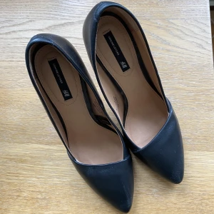 Svarta pumps, 36 - Säljer ett par snygga svarta pumps, skinn både in och utsidan. Använda en gång men har ett märke på klacken enligt bild. I övrigt bra skick. Klackhöjd ungefär 9.5cm.