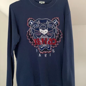 Kenzo tröja - Säljer nu min tröja då jag aldrig använder den. Endast använd fåtal gånger. Den är i bra skick, 8/10. Storlek xs men sitter som M (Stor i sin storlek). Plagget är äkta, köpt på NK och kvittot medföljer. Ny pris: 2100