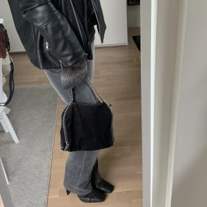 Väska - Stella McCartney liknande svart väska med kedjedetaljer. Okänt märke. Går att stänga med dragkedja. Fint skick! Går att ha på axeln! 
