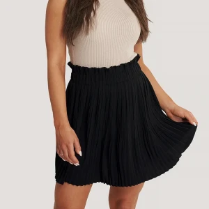 Svart minikjol  - Säljer denna jättesköna minikjolen som har en hög elastisk midja med veckad design och en liten volangdetalj i storlek 36 från NAKD. Såå fin och lätt att både klä upp och klä ner❣️