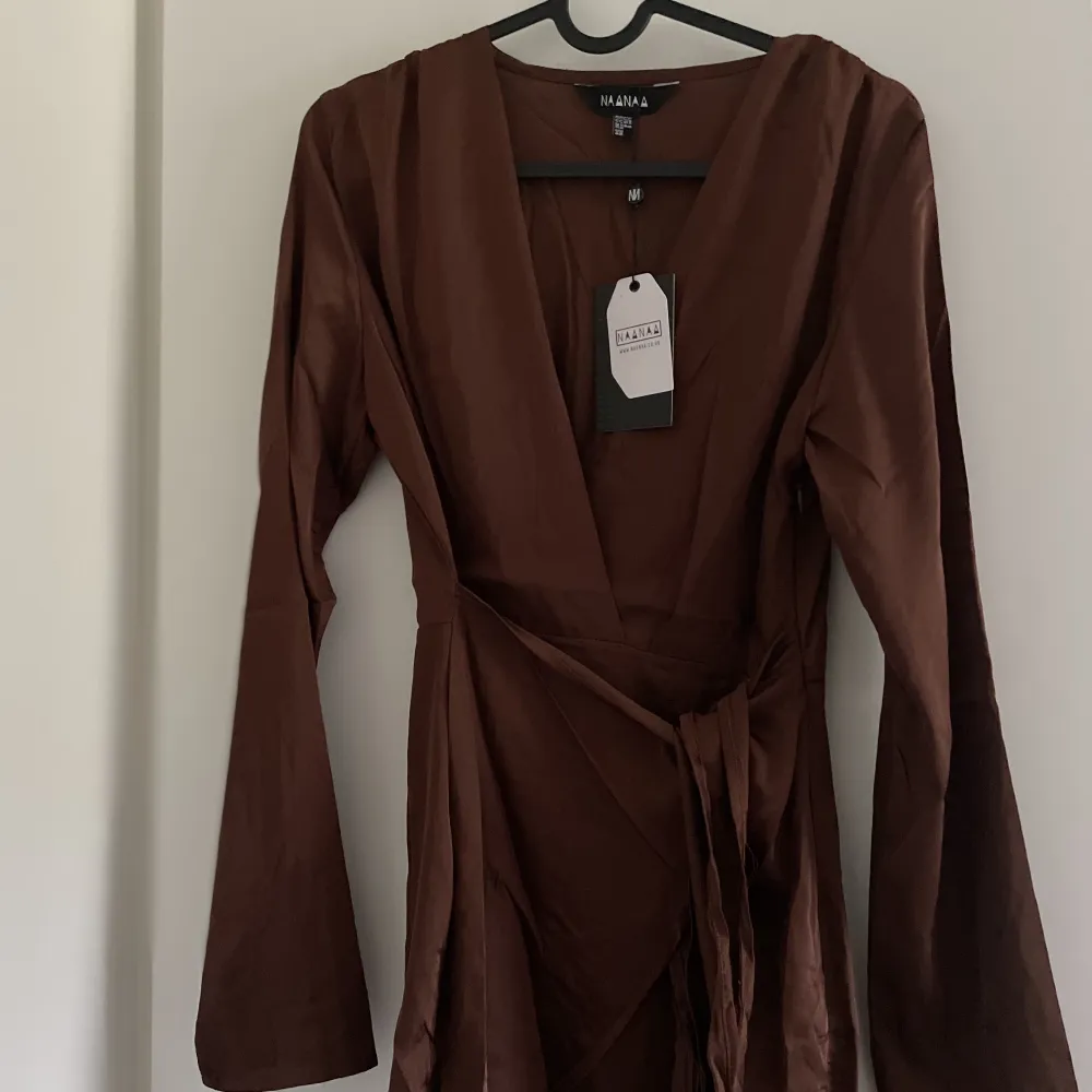 En brun oanvänd silkesklänning från Asos. Sitter väldigt fint runt kroppen och ett snöra där du kan reglera hur tajt den ska sitta vid midjan! 🤎. Klänningar.