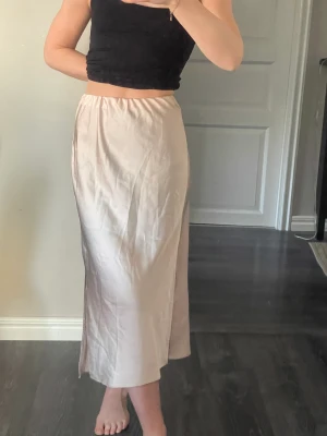 Satinkjol med slits - Beige/ljusrosa satinkjol från ASOS. Använd max två gånger. Strl 38.