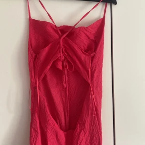 Långklännig med öppen rygg - En knallrosa långklänning som har knytning där bak och öppen rygg. 