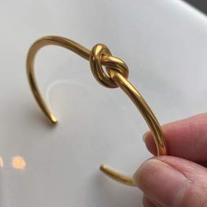 Guldarmband i märket Wos med en knut. 