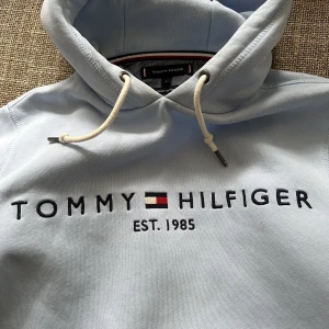 Tommy Hilfiger regular hoddie small - Säljer en ljusblå Tommy H hoddie i Organic cotton. Väldigt lite använd &  omsorgsfullt omskött.