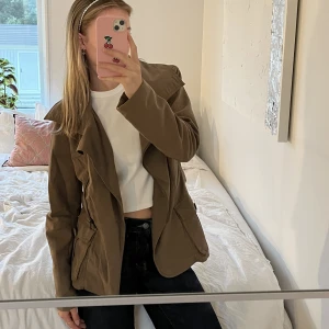 Olivgrön trench jacka  - Olivgrön jacka i en kortare trenchcoat modell. Väl omhändertagen. 