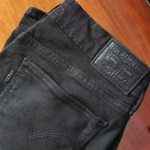 Levis 715 bootcut - Svarta jeans från levis, storlek 28,använda ca två gånger så är i fint skick. Två sista bilderna är lånade då jeansen inte passar mig längre. Midja: 37 cm, längd insida ben: 82, grenen framtill 21 cm. Finns djur i hemmet. Kan skicka mer bilder vid behov. 