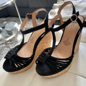 Nya kilklackar svarta kork 37 - Snygga bekväma kilklackar i svart med ställbar rem i vristen. Fin passform. Stl 37