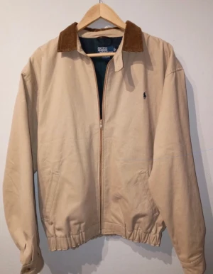 Ralph Lauren jacka - Skitsnygg vintage vår/höst jacka av märket Ralph Lauren. Den har en fläck som du kan se på bilden som knappt syns när den e på dig. Den är ljus brun med en cord crage. Storlek är Medium. Skriv om du har fler frågor//emstreet 