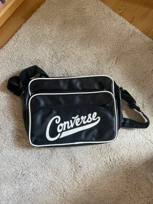 Converse väska  - Rymlig svart väska med vitt tryck.  Har även ett datorfack.  Mått ca 39x31 cm. 