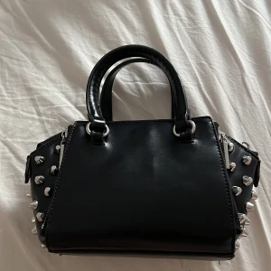 Handväska med nitar⚡️ - Det finns ettt stort fack sen två mindre fack på varsin sida av utsidan och ett mindre fack inuti!! 