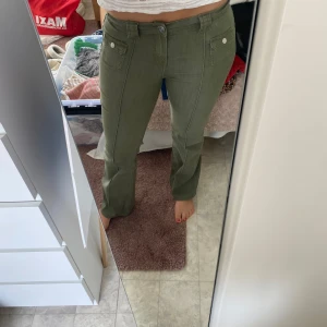 Gröna byxor från H&M - Säljer ett par gröna byxor från H&M:s kollektion Divided. De har en snygg och stilren design med knappar framtill och fickor. Perfekta för en casual look eller att klä upp med en snygg topp. Byxorna är i storlek 40 och passar perfekt för vår och höst.