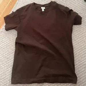 Säljer en enkel och stilren brun t-shirt från H&M Basics. Perfekt för vardagsbruk med en normal passform och korta ärmar. Gjord i mjukt bomullsmaterial för extra komfort. Passar bra till både jeans och shorts!