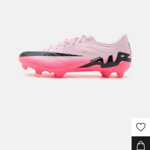 Nike fotbollsskor i rosa och svart - Snygga fotbollsskor från Nike i en cool rosa färg med svarta detaljer. Skorna har en modern design med snörning och är perfekta för fotbollsträning eller match. De är lätta och ger bra grepp på planen.