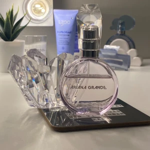 Ariana Grande parfym - Säljer en superfin parfym från Ariana Grande. Flaskan är rund och genomskinlig med en ljuslila ton och har ett coolt kristallformat lock. Den ser verkligen lyxig ut och är perfekt för att ha framme på sminkbordet. Doften är söt och fräsch, perfekt för både vardag och fest! Sparsamt använd 
