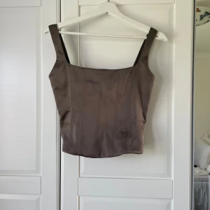 Korsett topp från Zara - Olivgrön korsett topp från Zara. Köpt i januari detta år men har endast använts en gång. Finns en liten fläck på ett av banden. 