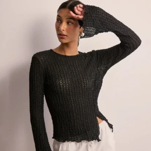 Svart ribbad tröja från Gina Tricot - Snygg svart ribbad tröja från Gina Tricot med långärmad design. Perfekt för lager-på-lager eller som statement-plagg. Den har en stilren look med en lätt transparent finish.