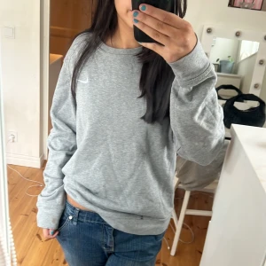 Grå sweatshirt från Nike - Säljer en klassisk grå sweatshirt från Nike med rund hals och det ikoniska swoosh-loggan på bröstet. Jätteskön!