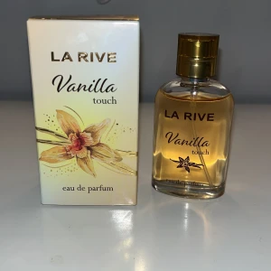 La Rive Vanilla Touch Eau de Parfum - La Rive Vanilla Touch är en eau de parfum med en söt och varm doft av vanilj. Flaskan är elegant och genomskinlig med en gyllene kork, och förpackningen pryds av en vacker vaniljblomma. Perfekt för dig som älskar mjuka och inbjudande dofter. Aldrig andvänt