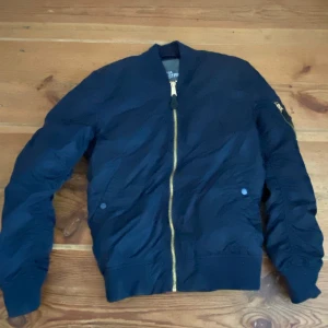 Jacka från Alpha Industries - Mörkblå bomberjacka från Alpha Industries. Lite tjockare än en vanlig vårjacka. Det är min brorsas, men jag kan få fram fler detaljer om du vill veta mer :)