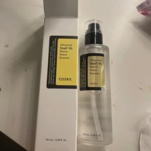 COSRX Advanced Snail 96 Mucin Power Essence - En återfuktande essens från COSRX med snigelsekretfiltrat som hjälper till att reparera och återfukta huden. Flaskan innehåller 100 ml och har en praktisk pump för enkel applicering. Perfekt för att ge huden en mjuk och smidig känsla.
