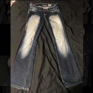 Mörkblå bootcut jeans från Young age  - Snygga mörkblå bootcut jeans med slitna detaljer. mått:40cm tvärs över midjan och 103 cm ytterben