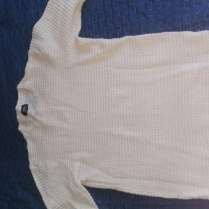 Beige tröja från Smog - Säljer en beige tröja från Smog med ett diskret ribbat mönster. Tröjan har långa ärmar och en rund halsringning, perfekt för en stilren look.