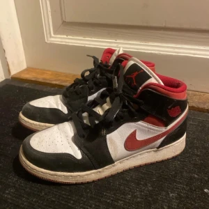Nike Air Jordans i svart, vitt och rött - Snygga Nike Air Jordans i klassisk färgkombination av svart, vitt och rött. Skorna har snörning och en ikonisk design med Nike-logga på sidan.                          Fint skick, tvättas innan postning såklart! 🩷