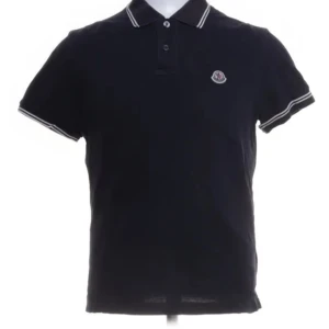 Svart pikétröja från Moncler - Snygg svart pikétröja från Moncler med klassisk krage och knappar. Tröjan har korta ärmar och ett broderat Moncler-märke på bröstet. Perfekt för en stilren look.