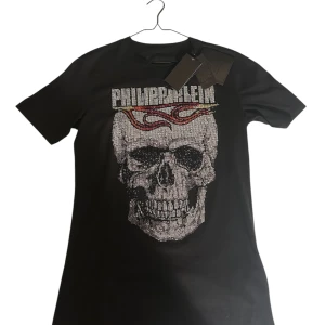 Philipp Plein T-shirt Flames SS - Cool svart t-shirt från Philipp Plein med en stor glittrig dödskalle på framsidan och text på baksidan. Tillverkad i 100% bomull för en bekväm passform. Perfekt för dig som vill sticka ut med en edgy stil.