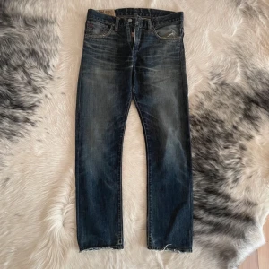 Jeans från Polo Ralph Lauren - Snygga jeans från Polo Ralph Lauren i en klassisk blå denim. De har en straight passform med låg midja och slitna detaljer för en trendig look. Perfekta för en avslappnad stil.