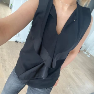 Svart blus - Jättesöt svart blus med volanger. Insydd på sidorna men går att sprätta, den har en guldknapp upptill om man vill knäppa💗