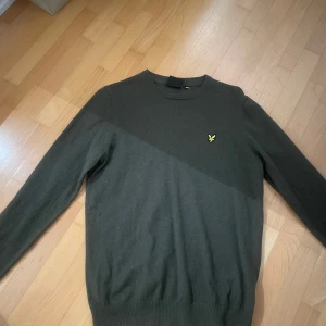 Grön tröja från Lyle & Scott - Snygg grön tröja från Lyle & Scott med deras ikoniska logga på bröstet. Tröjan har en klassisk passform och är tillverkad i ett mjukt material som passar perfekt för kyligare dagar.