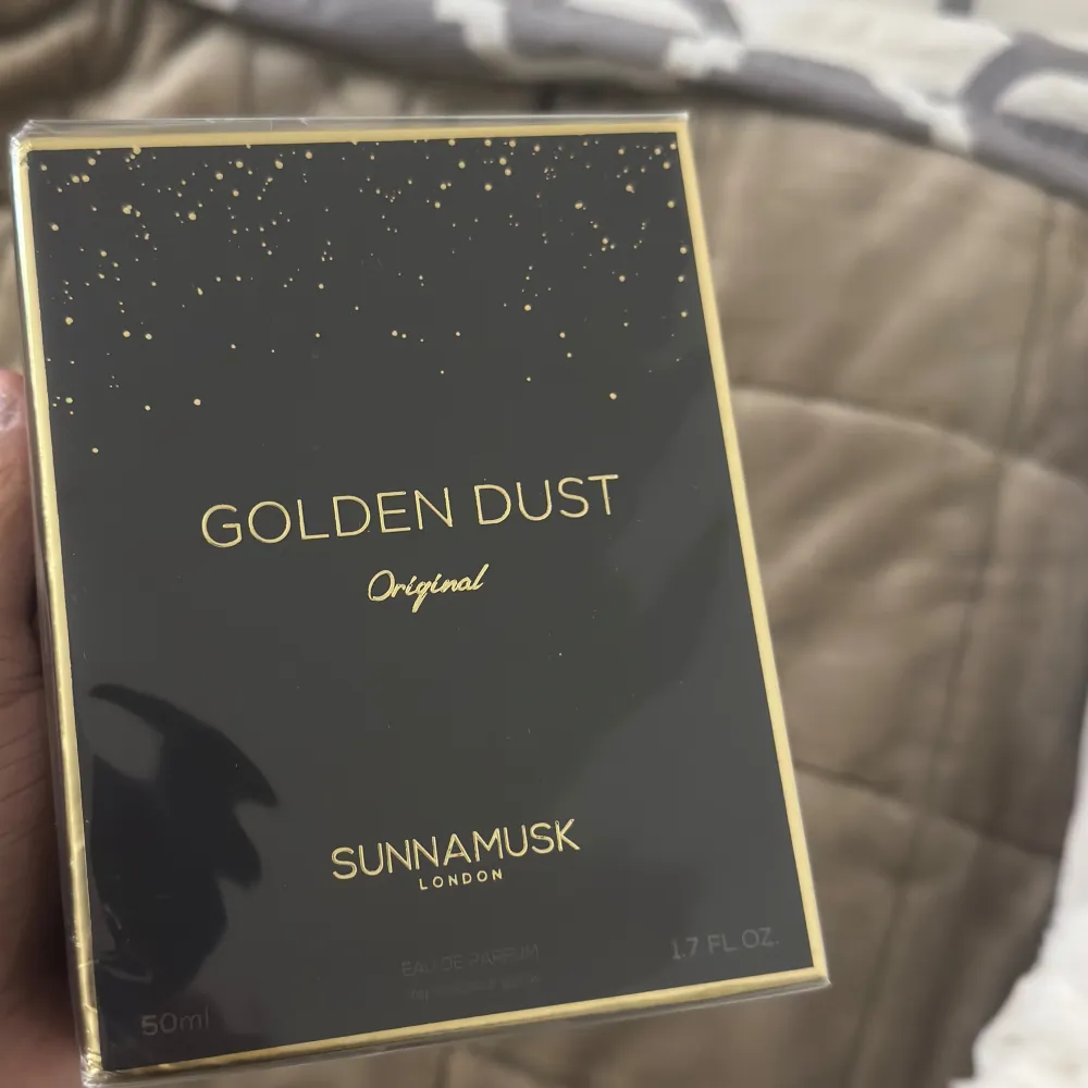 Golden Dust Original från Sunnamusk är en elegant parfym i en stilren svart förpackning med gyllene detaljer. Flaskan rymmer 50 ml av denna exklusiva doft, perfekt för den som söker något unikt och sofistikerat. Säljs för 950kr . Perfume.
