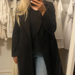 Svart långkappa med knytband - Snygg svart kappa med knytband i midjan. Perfekt för kyligare dagar och ger en stilren look. Långärmad design som passar bra till både jeans och klänning. Kappan är ca 107cm lång totalt. 🧸🌸 små nopprig om man är känslig för de syns sista bilden