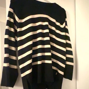 Svart och vit randig tröja - Säljer en stilren svart och vit randig tröja med långa ärmar. Perfekt för en avslappnad look. Tröjan har en klassisk design med breda ränder.