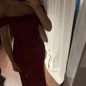 Balklänning - Elegant vinröd balklänning med offshoulder-design och en smickrande slits framtill. Använd en gång.