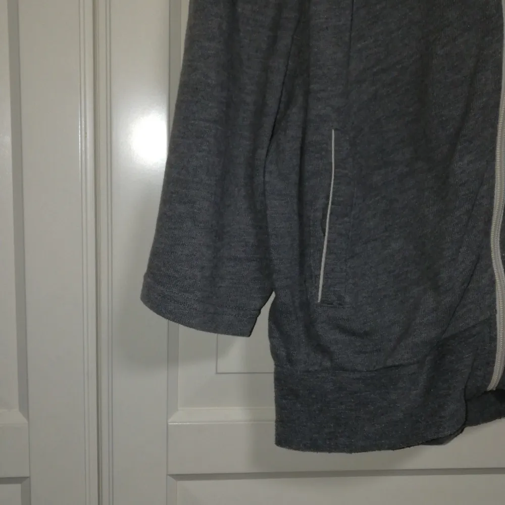 Mysig grå hoodie från Bik Bok med dragkedja och justerbar huva. Tröjan har trekvartsärmar och praktiska fickor framtill. Perfekt för en avslappnad stil.. Neuletakit & Villapaidat.