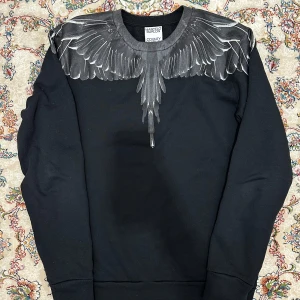 Marcelo Burlon tröja - Snygg svart sweatshirt från Marcelo Burlon med ett coolt vingtryck över axlarna och bröstet. Storleken är XS men passar S