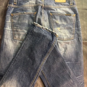Nudie slim jeans med slitningar, modell grim tim - Mycket fint skick, modell grim tim, size 32/32 för stora på mig 180 63 kg men går med bälte. Mått 43 midja, 106 längd. 