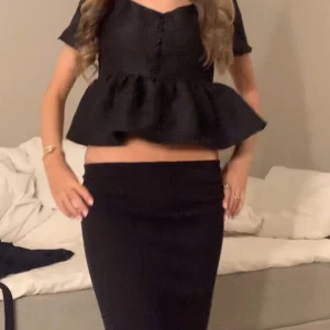 Svart blus med volangdetalj - Snygg svart blus med korta ärmar och volangdetalj i nederkant. Blusen har knappar framtill🤍Skulle säga att den passar s-xxs💗💗