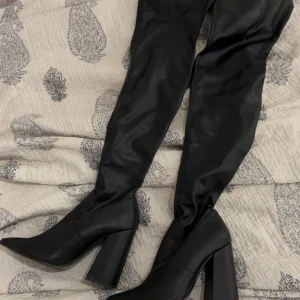 Svarta stövlar från Steve Madden - Snygga svarta stövlar från Steve Madden i skinn med hög klack och spetsig tå. Perfekta för att ge en elegant touch till din outfit. De är knähöga och har en stilren design.