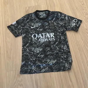 Fotbollströja med Coolt mönster - Säljer en svart PSG fotbollströja med ett unikt mönster och vit text. Tröjan är kortärmad och har sponsorloggor på framsidan. Perfekt för fans av laget och fotbollsentusiaster. OBS DETTA ÄR INGEN OFFICIELL MATCH TRÖJA. Storleken 176 Men den är väldigt liten i storleken så allla mellan 150-165 passar. PRIS GÅR ATT DISKUTERA