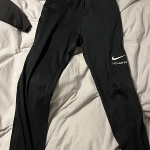 Svarta träningsbyxor med Neymar-tryck - Snygga svarta träningsbyxor med Neymar-tryck och Nike-logga. Byxorna har gula detaljer längs sidorna och är perfekta för fotbollsträning. De är designade för att ge en bekväm passform och rörelsefrihet.