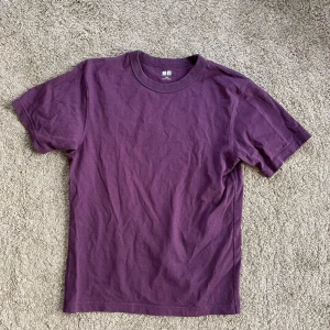 Lila t-shirt från Uniqlo - Säljer en stilren lila t-shirt från Uniqlo i storlek XS. Den har en klassisk rund hals och korta ärmar, perfekt för en avslappnad look.