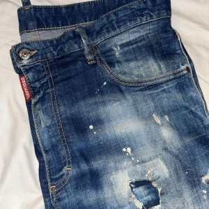 Blå jeans från Dsquared2 - Använda max 5 gånger om ens de. Säljer för dom är för stora i midjan på mig men bra i längden, är 1,80. blå jeans från Dsquared2 med slitna detaljer och en cool tvättad look. De har en dragkedja och knapp framtill samt klassiska fem fickor. Perfekta för en avslappnad stil med en touch av edge.
