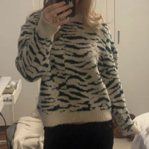 Stickad tröja zebra mönster - Säljer en jättefin vit och mörkgrön stickad tröja från hm, köpte på plick. Har sytt i den vid axlarna då den hade som axelvaddar innan, därför tröjan sticker ut lite på armarna. Fråga om mer bilder och pris går att diskutera🥰