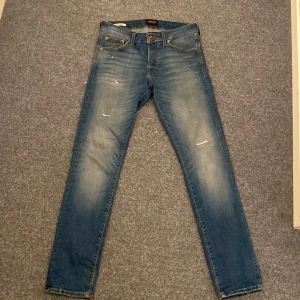 Blå slim jeans från Jack & Jones - Snygga blå slim jeans från Jack & Jones med en modern tvätt och slitna detaljer. Perfekta för en stilren look. De har en klassisk femficksdesign och knappgylf. Nyskick använda runt 4 gånger. Hör av dig vid funderingar!